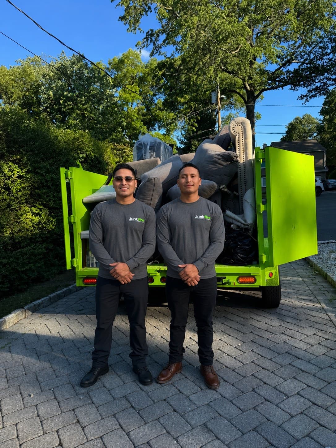 Junkfire team standing in front of the green removal trailer